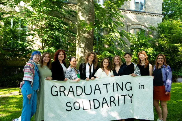Mastersstudenter med banderoll där der står "graduating in solidarity"